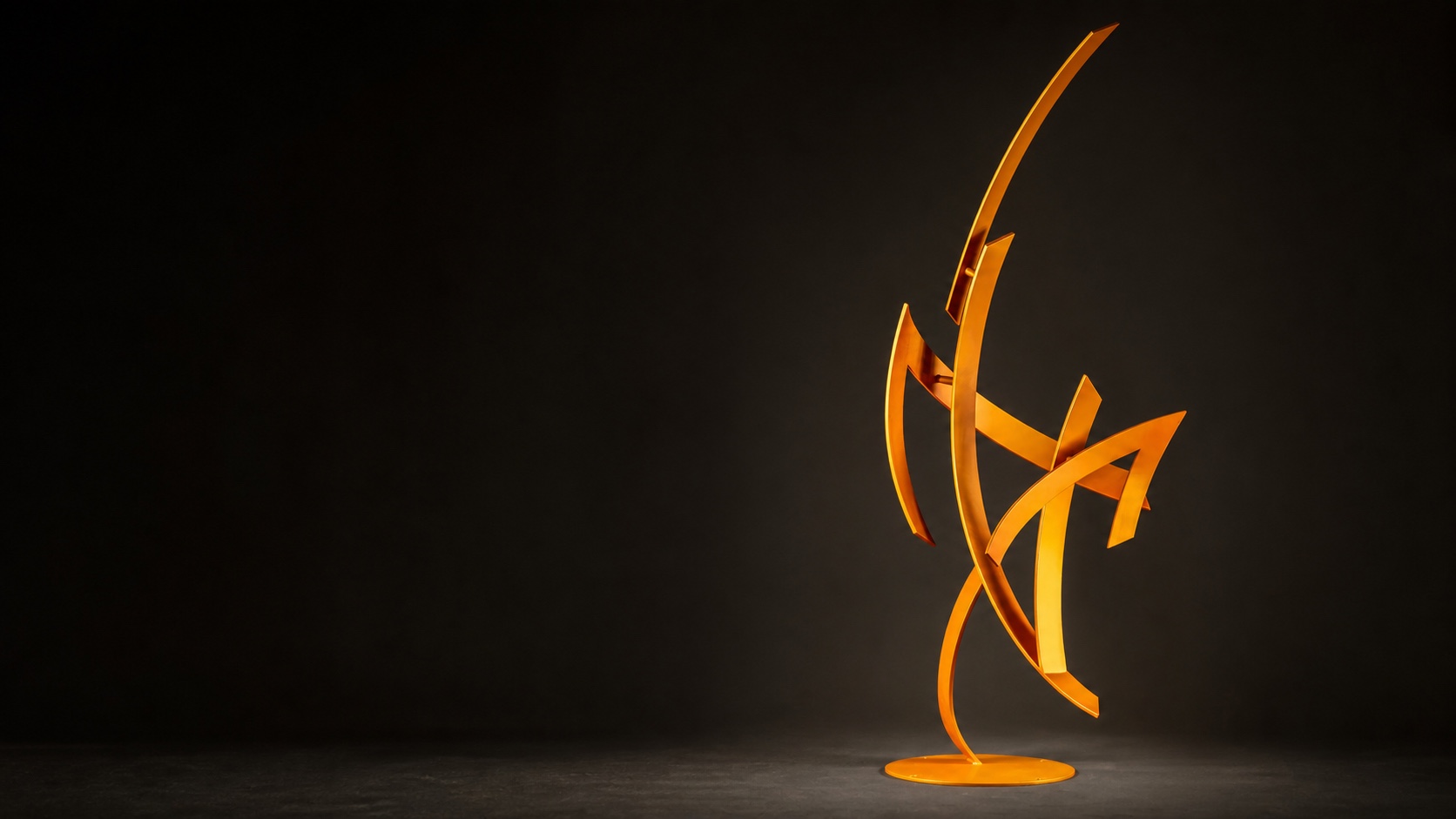 Orange abstract steel sculpture by Miguel Edwards against a charcoal gallery backdrop